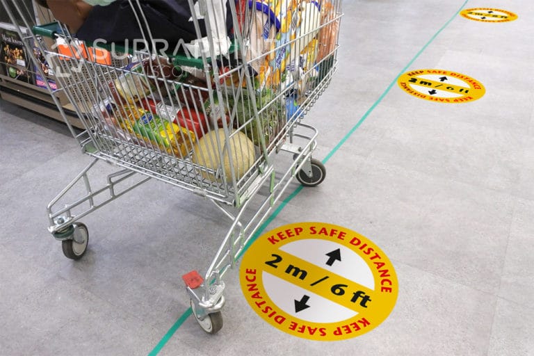 Social distancing marks on supermarket floor intended to stop or slow down the spread of a contagious Coronavirus (COVID-19) disease. Safety Floor Stickers Covid large format printing