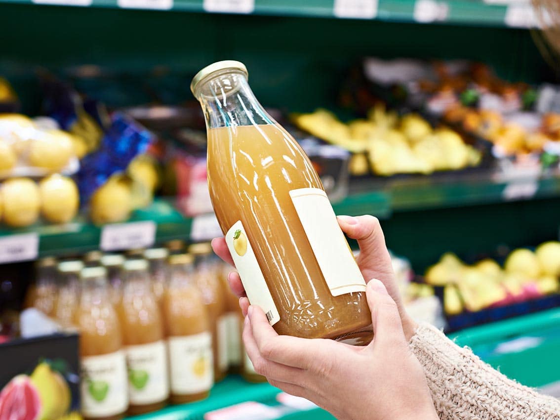 Hands with bottle of fresh apple juice in store